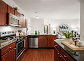 Thumbnail 1 of 38 - A kitchen with dark wood cabinets and a black counter top. at Aventura at Richmond, St. Peters, 63376