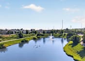 Thumbnail 40 of 41 - A serene park with a pond, a fountain, and a clear blue sky.