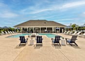 Thumbnail 2 of 36 - A large outdoor swimming pool area with sun loungers and a building in the background.