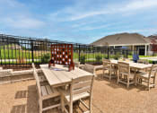 Thumbnail 27 of 28 - a patio with tables and chairs and a house in the background  at Aventura at Hawk Ridge, Missouri