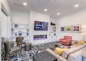 Thumbnail 6 of 31 - A living room with a grey sofa, a red chair, a black and white rug and a TV on the wall.