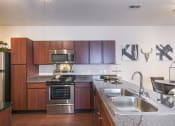 Thumbnail 5 of 31 - a kitchen with stainless steel appliances and wooden cabinets  at Aventura at Richmond, St. Peters