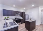Thumbnail 24 of 37 - a kitchen with white counter tops and dark cabinets and stainless steel appliances at Aventura at Towne Centre, Missouri