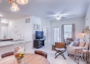Thumbnail 22 of 37 - a living room with a dining room table and a television at Aventura at Towne Centre, Ellisville, MO, 63011