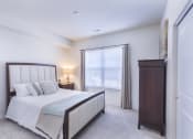Thumbnail 33 of 37 - a bedroom with a bed and a dresser and a window at Aventura at Towne Centre, Ellisville, 63011