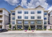 Thumbnail 2 of 29 - a large apartment building with cars parked in front of it at Aventura at Wild Horse Creek, Chesterfield, MO