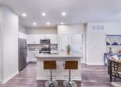 Thumbnail 20 of 29 - a kitchen with white cabinets and a counter top with three stools at Aventura at Wild Horse Creek, Chesterfield, 63017