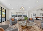 Thumbnail 9 of 16 - A living room with a glass table and grey couches.