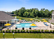 Thumbnail 19 of 41 - A large swimming pool surrounded by yellow umbrellas and blue chairs at Aventura at Wentzville I & II Apartments, Wentzville, 63385