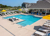 Thumbnail 18 of 41 - A large swimming pool surrounded by sun loungers and umbrellas at Aventura at Wentzville I & II Apartments, Missouri