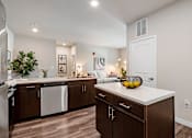 Thumbnail 4 of 41 - A modern kitchen with dark wood cabinets and white countertops at Aventura at Wentzville I & II Apartments, Wentzville, MO