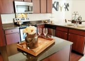 Thumbnail 3 of 31 - a kitchen with a wooden cutting board with a vase and glasses on a counter at Aventura at Richmond, Missouri, 63376