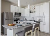 Thumbnail 19 of 37 - a kitchen with a large center island with a granite countertop at The Edison at Blue Springs, Blue Springs, 64014