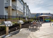Thumbnail 22 of 37 - an outdoor patio with tables and barbecue grills at The Edison at Blue Springs, Blue Springs, MO