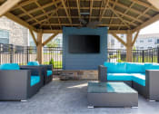 Thumbnail 6 of 37 - a patio with couches and a table in a pavilion with a television at The Edison at Blue Springs, Blue Springs, MO, 64014