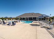 Thumbnail 36 of 36 - A pool area with sun loungers and a building in the background.