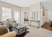 Thumbnail 32 of 41 - A living room with a glass coffee table and a brown rug at Aventura at Wentzville I & II Apartments, Wentzville, MO