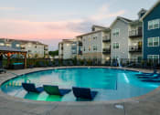 Thumbnail 27 of 37 - an apartment swimming pool with chairs at dusk at The Edison at Blue Springs, Missouri