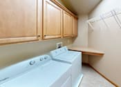 Thumbnail 24 of 28 - A white dryer is sitting in a laundry room with wooden cabinets.