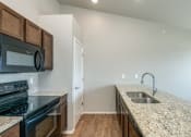 Thumbnail 31 of 41 - Kitchen with Granite Countertops and Black Appliances