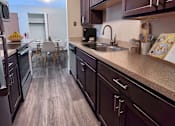 Thumbnail 4 of 18 - A kitchen with dark wood cabinets and a light brown floor.