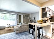 Thumbnail 2 of 18 - A modern kitchen with a dining table and chairs is adjacent to a living room with a couch and a coffee table.