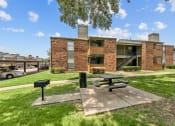 Thumbnail 28 of 50 - a picnic area with a grill in front of a building at The Hills at Ironhorse, North Richland Hills, 76180