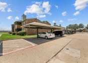 Thumbnail 40 of 50 - a parking lot with cars parked in front of a brick building at The Hills at Ironhorse, North Richland Hills