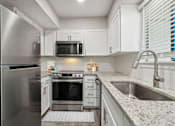 Thumbnail 1 of 68 - large kitchen with white cabinets, granite countertops and stainless steel appliances at The Escapade, San Antonio, TX