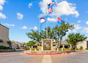 Thumbnail 15 of 40 - The image shows a sign that says "Highland Ridge" in front of a building with multiple flags flying in the background.