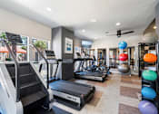 Thumbnail 24 of 40 - A gym with treadmills, elliptical machines, and exercise balls.