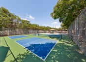 Thumbnail 21 of 47 - a pickleball court with blue and green courts and a fence