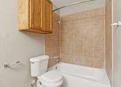 Thumbnail 11 of 19 - A bathroom with a toilet, tub, and wooden cabinet at Knoll Crest, San Antonio, Texas 78240