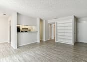 Thumbnail 50 of 68 - the living room and kitchen of a renovated apartment with white walls and wood floors at The Escapade, San Antonio, TX