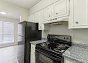 Thumbnail 51 of 68 - The Escapade apartment kitchen with black stove and refrigerator at The Escapade, San Antonio, Texas