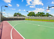 Thumbnail 36 of 40 - A basketball court with a red and green surface and a basketball hoop.