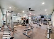 Thumbnail 17 of 47 - a gym with a lot of exercise equipment and a ceiling fan