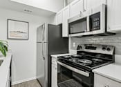 Thumbnail 1 of 40 - A black stove and microwave in a white kitchen.