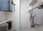 Thumbnail 28 of 28 - A hallway with a grey carpet and clothes hanging on the wall.