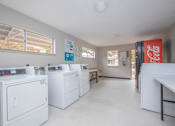 Thumbnail 11 of 12 - A laundry room with washers and dryers and a Coca-Cola fridge.
