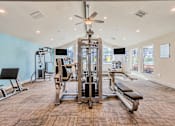 Thumbnail 21 of 23 - A spacious gym with a variety of equipment and a ceiling fan.