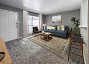 Thumbnail 21 of 28 - A living room with a blue couch and a rug.
