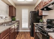Thumbnail 16 of 20 - A kitchen with brown cabinets and black appliances.at Alamo Park, San Antonio Texas  