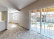 Thumbnail 38 of 47 - A room with a carpeted floor and a sliding glass door leading to a pool area.