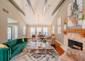 Thumbnail 12 of 20 - A living room with a green velvet sofa and a fireplace.