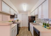 Thumbnail 2 of 20 - A kitchen with black appliances and wooden floors.
