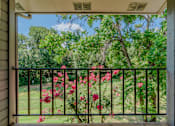 Thumbnail 10 of 20 - A balcony with a black railing and pink flowers in the foreground.