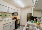 Thumbnail 1 of 20 - A kitchen with a black refrigerator and a stove top oven.
