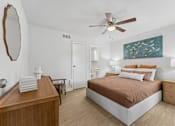 Thumbnail 8 of 20 - Bedroom with ceiling fan and coastal artwork at Knoll Crest Apartments, San Antonio, TX 78240