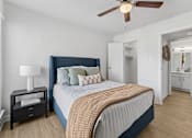 Thumbnail 6 of 20 - Bedroom with blue upholstered bed and en suite bathroom at Knoll Crest Apartments, San Antonio, 78240